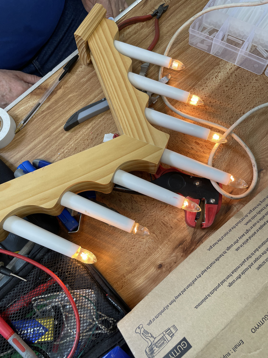 A wooden candle bridge light being tested on a repair table