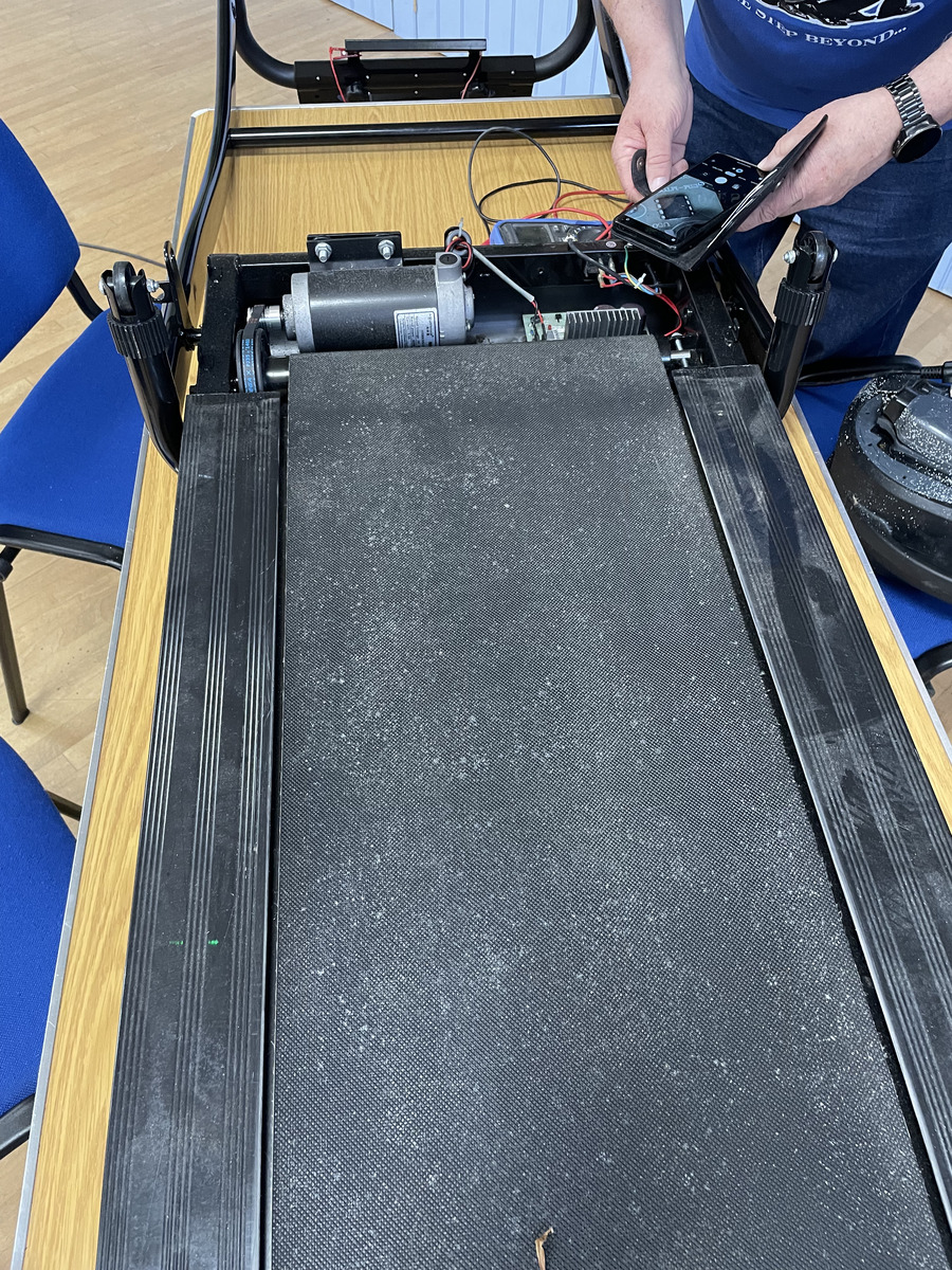 A treadmill belt and frame being inspected during a repair session