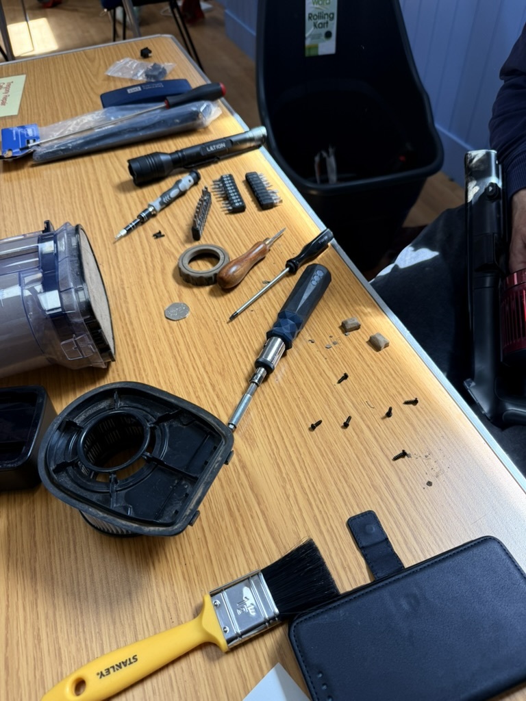 An opened handheld vacuum cleaner with parts laid out on a repair table