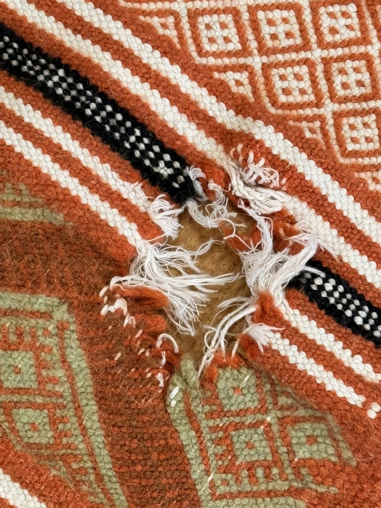 A chewed patterned blanket awaiting textile repair